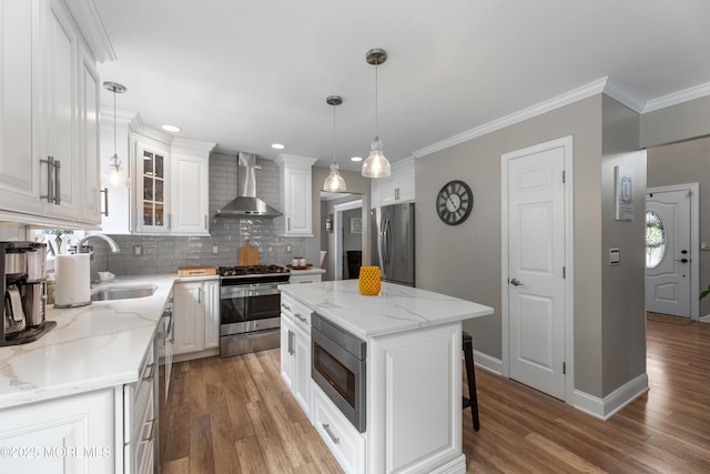 36 Sally St, Howell, NJ 07731 - kitchen with wall chimney exhaust hood, appliances with stainless steel finishes, backsplash, white cabinets, and light wood-style floors