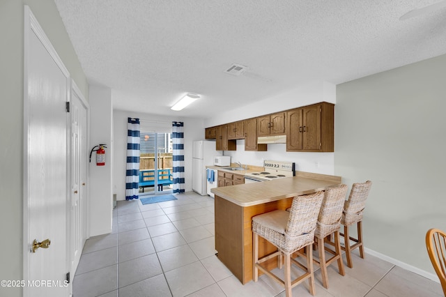 3100 Rte 35 Unit 6, Lavallette, NJ 08735 - kitchen featuring white appliances, light countertops, under cabinet range hood, a textured ceiling, and a kitchen breakfast bar