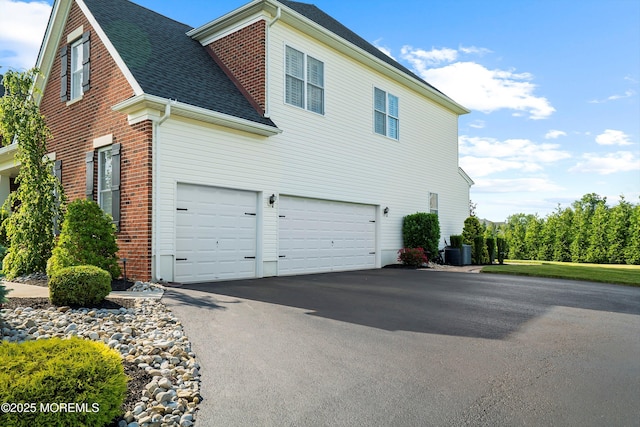 11 Potomac Ct, Freehold, NJ 07728 - view of side of property with asphalt driveway, brick siding, roof with shingles, and an attached garage