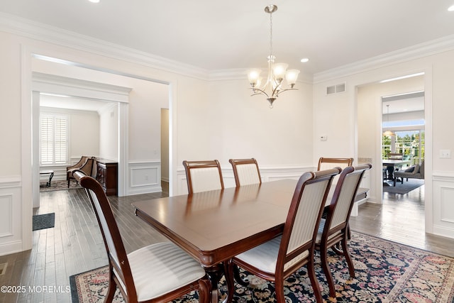 11 Potomac Ct, Freehold, NJ 07728 - dining area with a chandelier, a decorative wall, crown molding, dark wood finished floors, and wainscoting