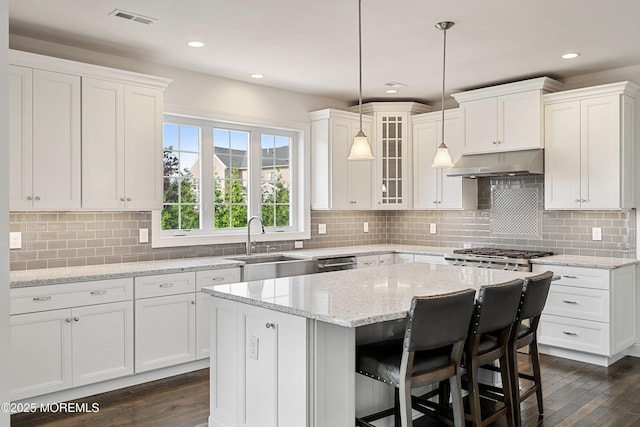11 Potomac Ct, Freehold, NJ 07728 - kitchen with under cabinet range hood, white cabinets, a kitchen island, glass insert cabinets, and recessed lighting