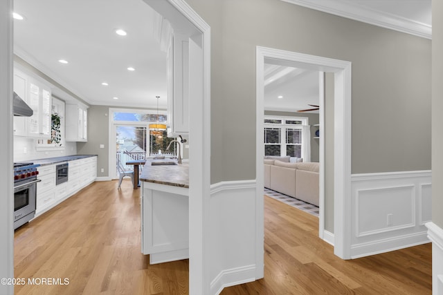 209 Sanborn Ave, Point Pleasant Beach, NJ 08742 - kitchen featuring designer stove, crown molding, white cabinetry, light wood finished floors, and wall chimney exhaust hood