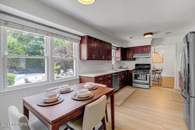 12 Neal Dr, Manalapan, NJ 07726 - kitchen with appliances with stainless steel finishes, under cabinet range hood, light wood finished floors, backsplash, and dark brown cabinets