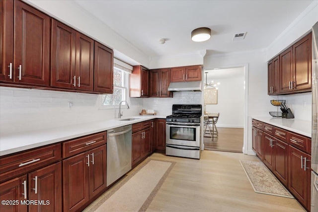 12 Neal Dr, Manalapan, NJ 07726 - kitchen featuring stainless steel appliances, under cabinet range hood, light wood finished floors, tasteful backsplash, and ornamental molding