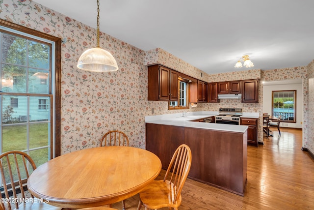 406 Bell Pl, Sea Girt, NJ 08750 - kitchen with white range with gas stovetop, wallpapered walls, under cabinet range hood, light countertops, and light wood finished floors