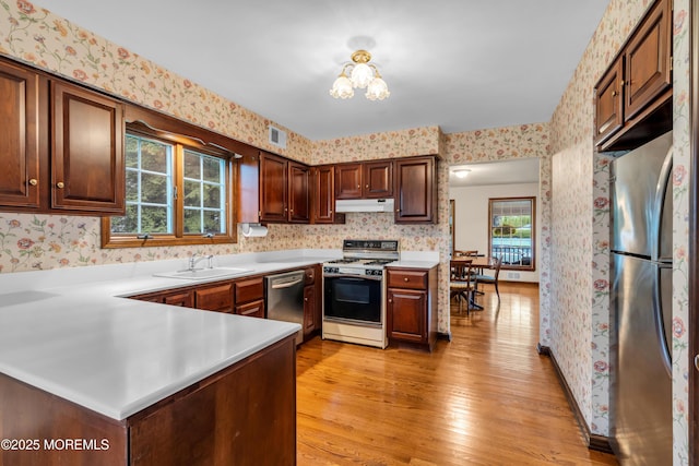 406 Bell Pl, Sea Girt, NJ 08750 - kitchen with stainless steel appliances, under cabinet range hood, wallpapered walls, plenty of natural light, and light wood-style flooring