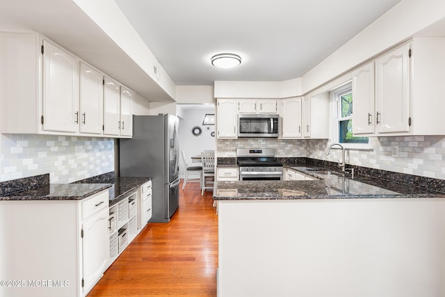8 Mendon Dr, Howell, NJ 07731 - kitchen featuring stainless steel appliances, dark stone counters, a peninsula, light wood finished floors, and tasteful backsplash