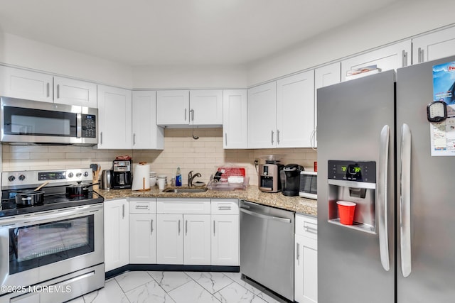 2508 Harmon Cv, Secaucus, NJ 07094 - kitchen with stainless steel appliances, light marble finish floors, white cabinets, and decorative backsplash