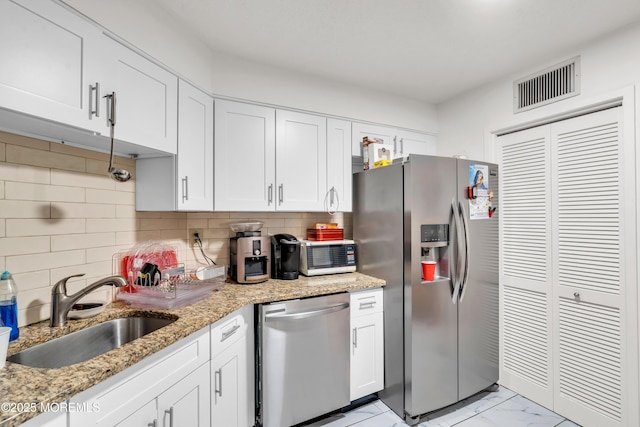 2508 Harmon Cv, Secaucus, NJ 07094 - kitchen with appliances with stainless steel finishes, light marble finish flooring, white cabinets, and decorative backsplash