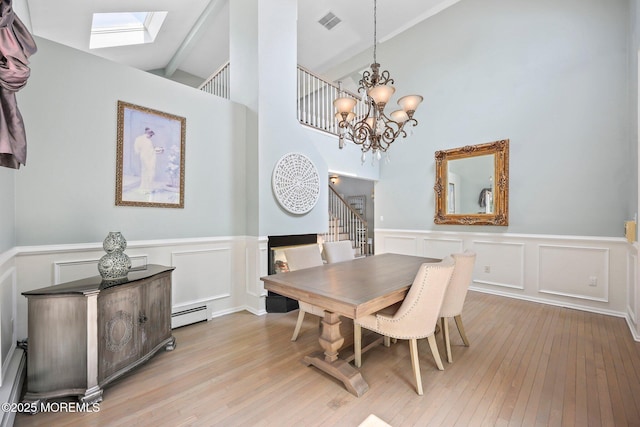 96 Kentucky Way, Freehold, NJ 07728 - dining space featuring a skylight, light wood-type flooring, a chandelier, a decorative wall, and a baseboard heating unit