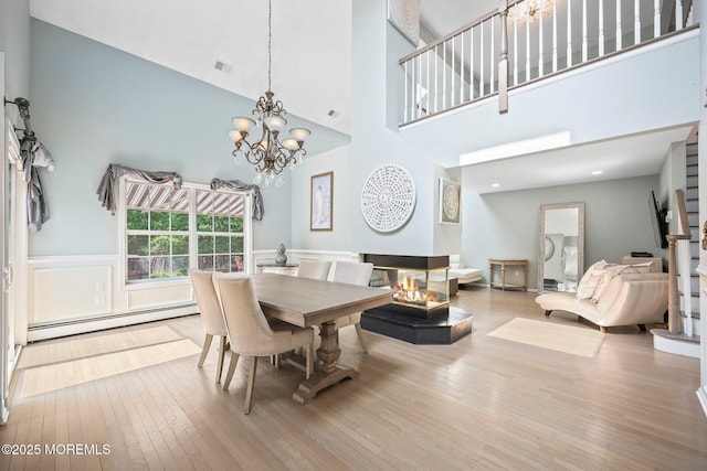 96 Kentucky Way, Freehold, NJ 07728 - dining room featuring wood-type flooring, baseboard heating, a towering ceiling, a chandelier, and wainscoting