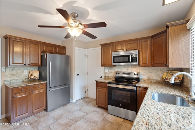 603-B Bosworth Ct, Manchester, NJ 08759 - kitchen featuring appliances with stainless steel finishes, ceiling fan, backsplash, light stone countertops, and brown cabinets