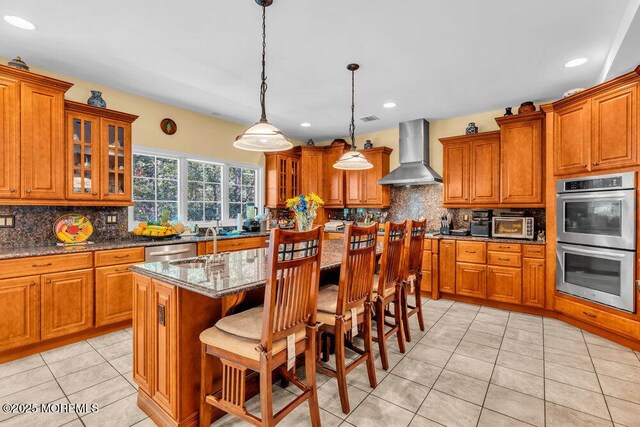 312 Clearstream Rd, Jackson, NJ 08527 - kitchen with wall chimney exhaust hood, stainless steel appliances, brown cabinets, decorative backsplash, and recessed lighting