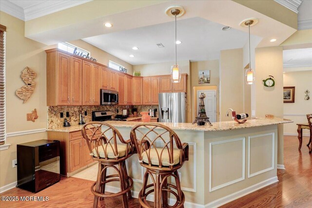 86 Wild Dunes Way, Jackson, NJ 08527 - kitchen with appliances with stainless steel finishes, decorative backsplash, a breakfast bar, light stone countertops, and ornamental molding