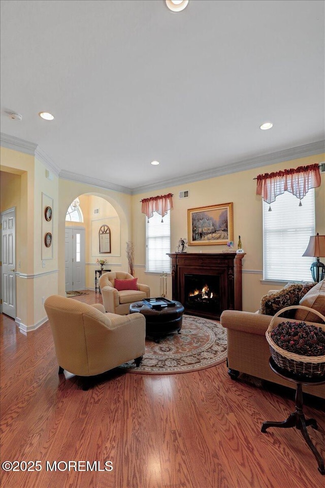 86 Wild Dunes Way, Jackson, NJ 08527 - living room with wood finished floors, a lit fireplace, crown molding, arched walkways, and recessed lighting