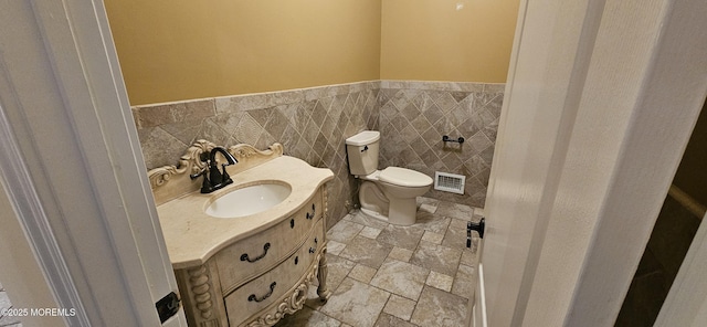 7 Quaker Hill Rd, Jackson, NJ 08527 - bathroom featuring vanity, stone tile floors, a wainscoted wall, and tile walls