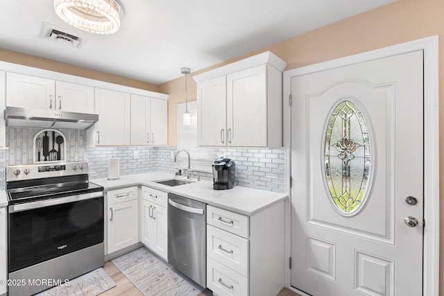 1058A Argyll Cir, Lakewood, NJ 08701 - kitchen with stainless steel appliances, under cabinet range hood, light countertops, backsplash, and white cabinets
