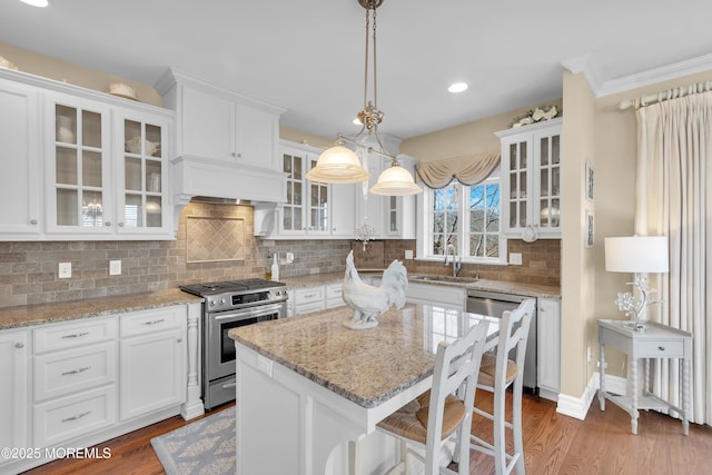 5-4 Main St, Oceanport, NJ 07757 - kitchen featuring appliances with stainless steel finishes, white cabinetry, a breakfast bar area, wood finished floors, and ornamental molding