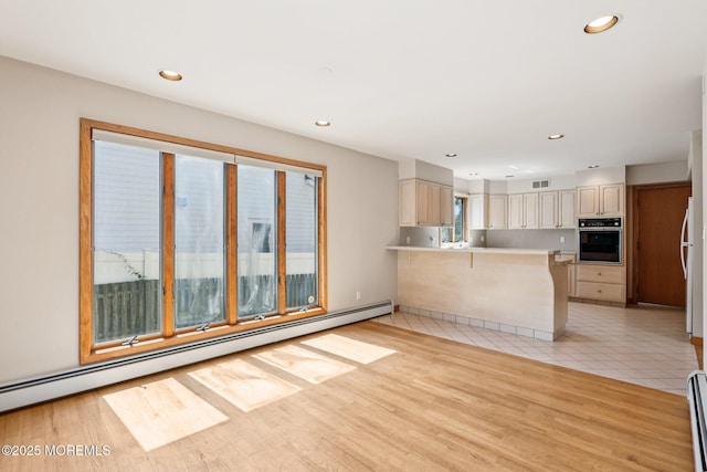 1120 Pennsylvania Ave, Manasquan, NJ 08736 - kitchen with black oven, a baseboard heating unit, a peninsula, a breakfast bar area, and light countertops
