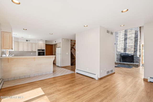 1120 Pennsylvania Ave, Manasquan, NJ 08736 - unfurnished living room with a baseboard radiator, light wood-style floors, recessed lighting, a brick fireplace, and stairs