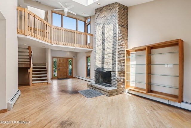 1120 Pennsylvania Ave, Manasquan, NJ 08736 - unfurnished living room with baseboard heating, a towering ceiling, stairs, wood finished floors, and a fireplace
