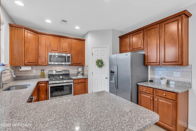 249 Chickadee Ct Unit 1000, Freehold, NJ 07728 - kitchen with stainless steel appliances, decorative backsplash, a peninsula, brown cabinets, and recessed lighting