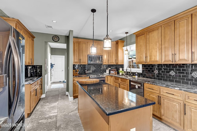 1020 Aumack Rd, Jackson, NJ 08527 - kitchen featuring appliances with stainless steel finishes, decorative backsplash, a center island, dark stone counters, and hanging light fixtures