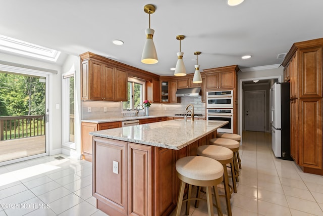 20 Birch Ln, Colts Neck, NJ 07722 - kitchen with white appliances, under cabinet range hood, tasteful backsplash, light tile patterned flooring, and brown cabinetry
