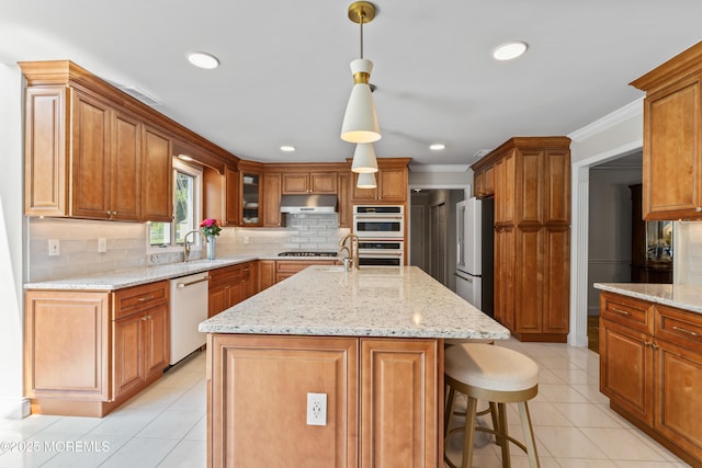 20 Birch Ln, Colts Neck, NJ 07722 - kitchen with under cabinet range hood, appliances with stainless steel finishes, decorative backsplash, a center island with sink, and light stone counters