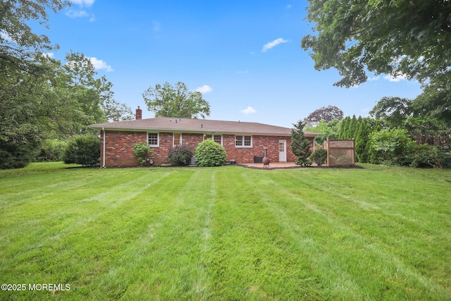 3 Mcelwaine Dr, Freehold, NJ 07728 - back of property featuring a chimney, a lawn, brick siding, and a patio area