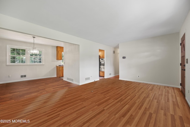 3 Mcelwaine Dr, Freehold, NJ 07728 - unfurnished living room featuring light wood-style floors and a chandelier