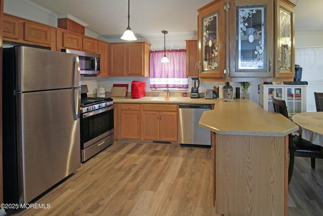26 Pine Ridge Blvd, Whiting, NJ 08759 - kitchen featuring appliances with stainless steel finishes, a peninsula, ornamental molding, light countertops, and light wood-style flooring