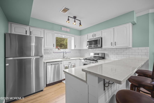 39 Sweet Gum Rd, Howell, NJ 07731 - kitchen featuring stainless steel appliances, a peninsula, white cabinetry, a breakfast bar area, and light stone countertops