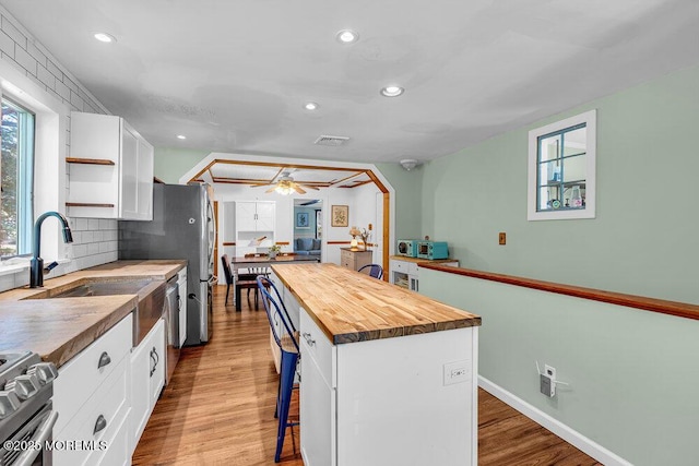276 Chandler Rd, Jackson, NJ 08527 - kitchen with butcher block counters, appliances with stainless steel finishes, white cabinetry, a breakfast bar area, and wood finished floors