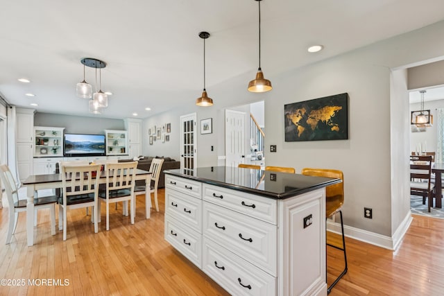 43 Sweet Gum Rd, Howell, NJ 07731 - kitchen featuring dark countertops, light wood-style floors, white cabinets, a kitchen bar, and pendant lighting