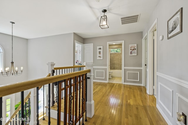 43 Sweet Gum Rd, Howell, NJ 07731 - hall featuring an upstairs landing, a chandelier, light wood-style floors, a wainscoted wall, and a decorative wall