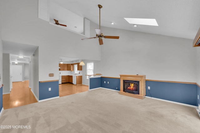 23 Dexter Ln, Jackson, NJ 08527 - unfurnished living room featuring light colored carpet, a ceiling fan, a glass covered fireplace, a skylight, and high vaulted ceiling