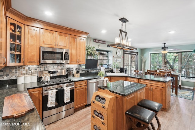 648 Point Ave, Brick, NJ 08724 - kitchen with appliances with stainless steel finishes, a peninsula, decorative backsplash, ceiling fan, and light wood-style flooring