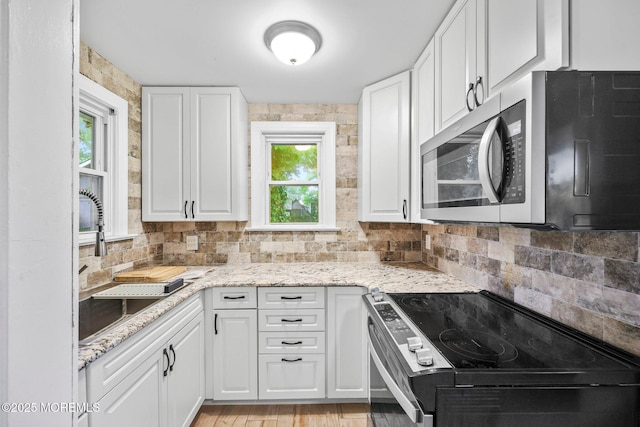 16 Steiner Ave, Neptune City, NJ 07753 - kitchen with stainless steel microwave, range with electric cooktop, backsplash, white cabinetry, and light stone counters