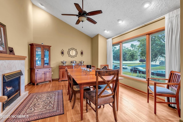 25 Canadian Woods Rd, Marlboro, NJ 07746 - dining area with light wood-style floors, ceiling fan, a textured ceiling, a glass covered fireplace, and high vaulted ceiling