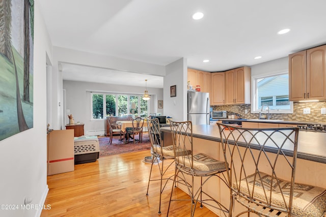 708 New York Blvd, Sea Girt, NJ 08750 - kitchen featuring freestanding refrigerator, light brown cabinetry, a breakfast bar, baseboard heating, and light wood finished floors