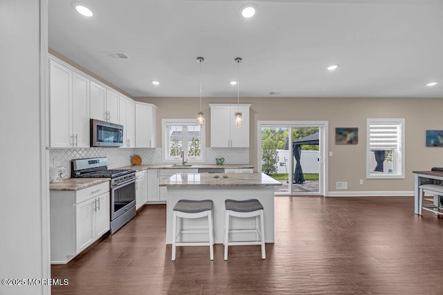 10 Willow Ave, Matawan, NJ 07747 - kitchen featuring appliances with stainless steel finishes, backsplash, a center island, a kitchen breakfast bar, and dark wood-style floors