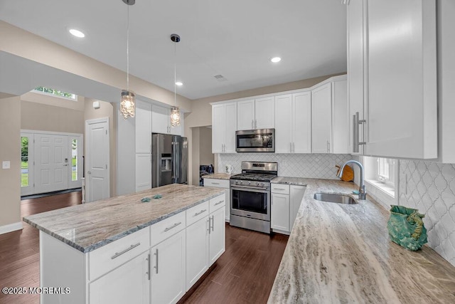10 Willow Ave, Matawan, NJ 07747 - kitchen with stainless steel appliances, a kitchen island, dark wood-style flooring, light stone counters, and tasteful backsplash