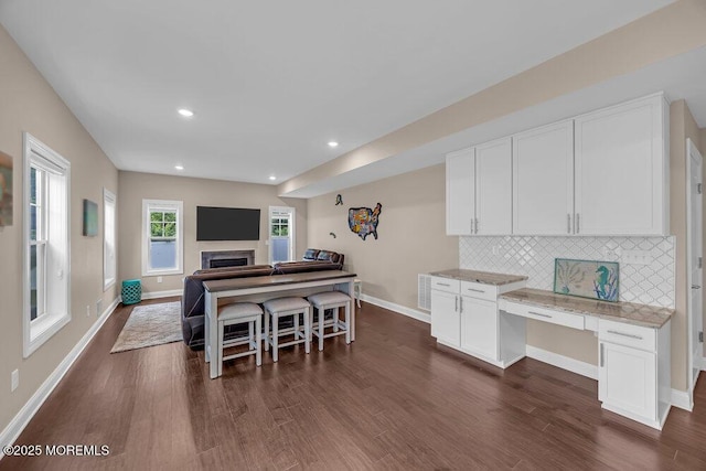 10 Willow Ave, Matawan, NJ 07747 - kitchen featuring dark wood-style floors, white cabinets, decorative backsplash, light stone counters, and a fireplace