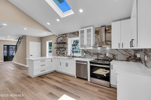 21 Harrison Ave, Englishtown, NJ 07726 - kitchen featuring stainless steel appliances, wall chimney range hood, a peninsula, a skylight, and white cabinets