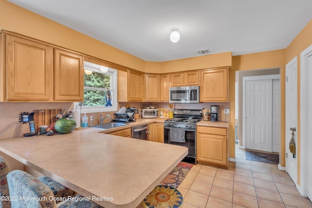 716 Hyson Rd, Jackson, NJ 08527 - kitchen with stainless steel appliances, a peninsula, light countertops, light brown cabinetry, and light tile patterned floors