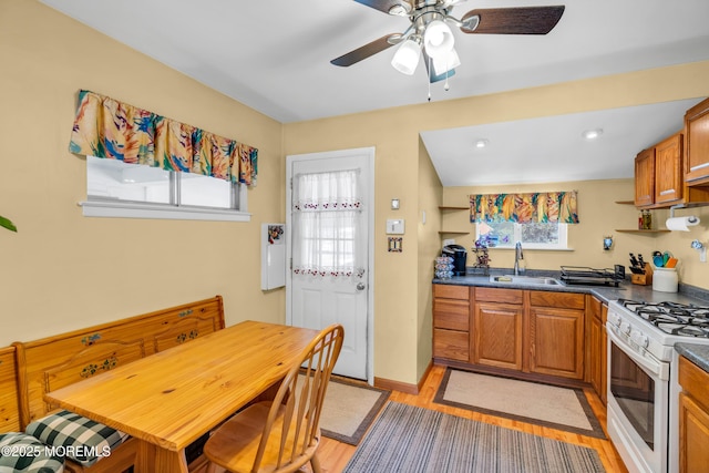 530 Aldrich Rd, Howell, NJ 07731 - kitchen featuring white gas range, dark countertops, light wood-style flooring, a ceiling fan, and brown cabinets