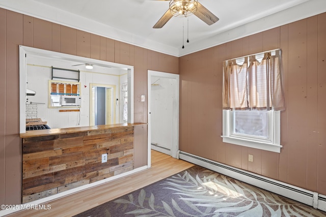 242 Sherman Ave, Seaside Heights, NJ 08751 - kitchen with a baseboard heating unit, white microwave, wood finished floors, a ceiling fan, and wooden walls