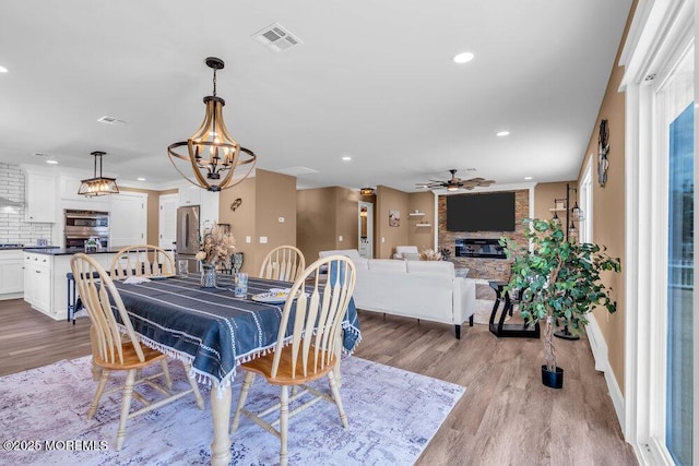 3 Andover Ct, Toms River, NJ 08757 - dining room featuring light wood finished floors, a large fireplace, a ceiling fan, recessed lighting, and a chandelier