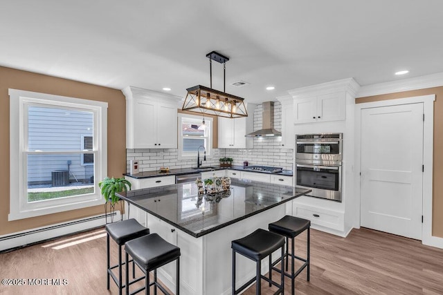 3 Andover Ct, Toms River, NJ 08757 - kitchen featuring wall chimney exhaust hood, appliances with stainless steel finishes, a kitchen bar, baseboard heating, and white cabinetry